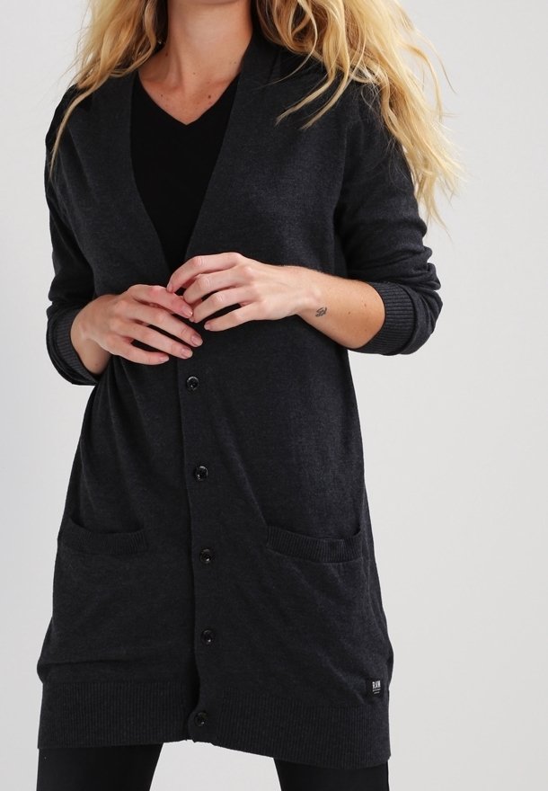Cardigan long gris foncé en matière douce. Il présente un col en V, des manches longues, une fermeture à boutons à l'avant, deux poches avant et des poignets et un ourlet côtelés.