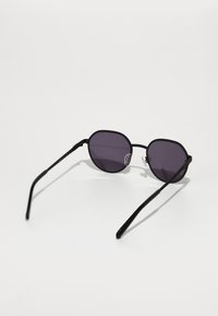 Ochelari de soare black metal cu lentile ovale de culoare mov. Ramă subțire, pârghii elegante și pernuțe de nas transparente. Design minimalist cu linii curate.