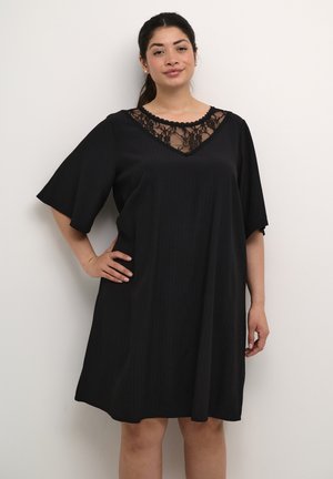 Robe noire en A avec des manches courtes et un décolleté en dentelle en V. Le tissu présente une texture côtelée subtile, améliorant le design global.