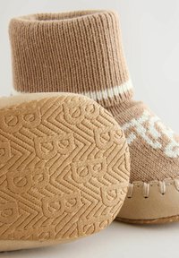 Pletená hnědá bota s vysokým žebrovaným vrškem a bílými pruhy, se strukturovanou béžovou podrážkou se zigzagovými vzory a logy.