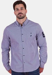 Chemise à manches longues pour homme dans un motif vichy violet et blanc. Comprend une poche avant et un accent numéro 8 sur la manches. Matériau en coton.