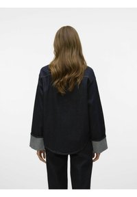 Mörk denimskjorta med avslappnad passform, med kontrasterande ljusa denimmanschetter och rundad nederkant. Mjuk textur med minimala sömnadsdetaljer.