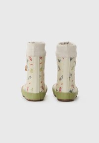 Bottes de pluie avec une base crème, des semelles vertes et un motif floral d'insectes. Présente un col souple et élastique en haut pour un ajustement réglable.