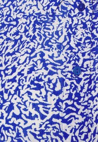 Camicia in tessuto blu e bianco con motivo astratto, chiusura a bottoni e colletto. Texture morbida in cotone.