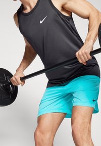 Débardeur de sport sans manches noir et shorts teal avec un design dégradé, comportant un petit logo Nike noir sur chaque vêtement.