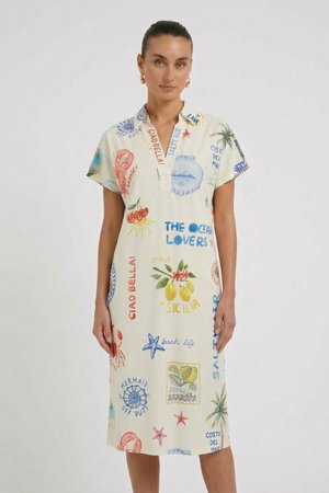 Frau trägt ein cremefarbenes kurzärmeliges Kleid mit bunten, thematisch ans Meer angelehnten Drucken und Sprüchen wie „Ciao Bella“ und „The Ocean Lovers.“