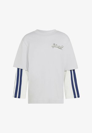 Witte, langarmige, gelaagde T-shirt met blauwe Adidas-strepen op de binnenkant van de mouwen en een klein Adidas-logo met sterren op de linker bovenborst.