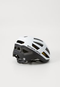 Weißer und schwarzer Fahrradhelm mit Belüftungsschlitzen, versehen mit einem Markenlogo, auf einem hellgrauen Hintergrund platziert.
