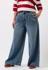 Wijdvallende blauwe denim jeans met een relaxed fit, voorzien van een hoge taille, een paar voorzakken en een licht vervaagde structuur.