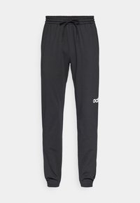 Sorte joggebukser laget av mykt stoff, med elastisk midje og snor, samt en hvit logo på venstre ben. Innstrammet ved anklene.