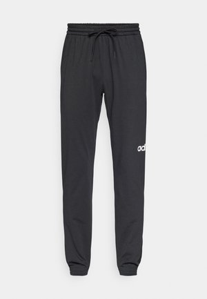 Musta dressipluus pehmest kangast, elastse vöökoha ja paelaga, millel on valge logo vasakul jalal. Kitsenevad pahkluude juures.