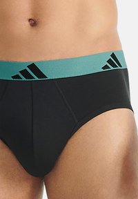 Svarta kalsonger med en turkos midjeband som har svarta diagonala ränder och Adidas-logotyp. Tillverkade av elastiskt material för komfort.