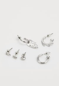 Sølvøreringer med et sett med ulike design: flamme, ring og stift stiler. Materialene er blank metall med glatte teksturer og detaljerte aksenter.
