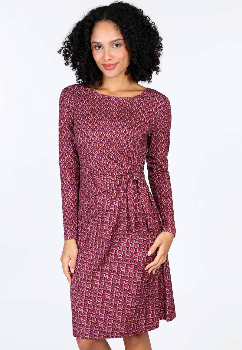 Langärmliges Kleid mit lila und rosa Muster, das ein Wickeldesign mit seitlichem Bindeband aufweist. Glatter, elastischer Stoff, knielanger Schnitt.