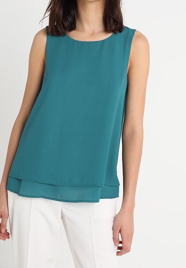 Top sans manches teal avec un col rond, présentant un design à ourlet superposé et un tissu doux et léger. Pas d'embellissements visibles.