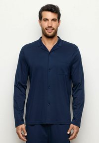 Camisa de pijama de manga larga en color azul marino, fabricada en un material suave, con cuello, botones frontales y un bolsillo en el pecho como detalle.