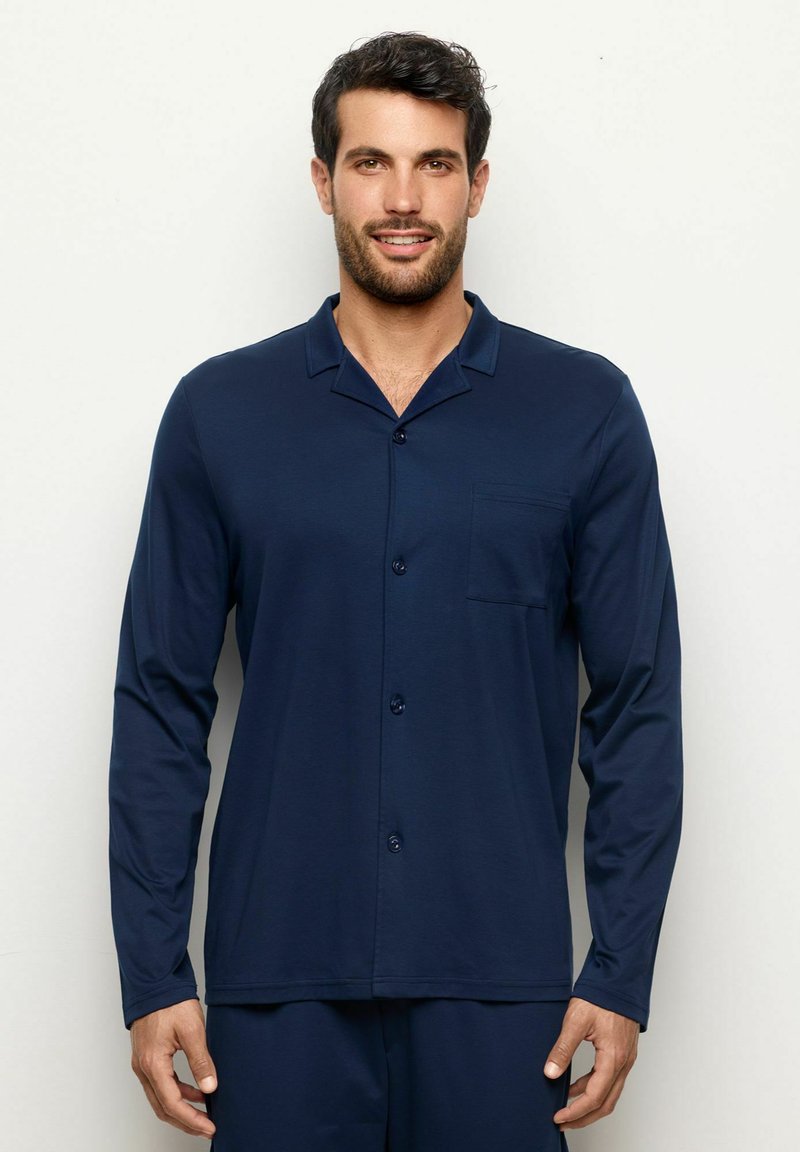 Camisa de pijama de manga larga en color azul marino, fabricada en un material suave, con cuello, botones frontales y un bolsillo en el pecho como detalle.