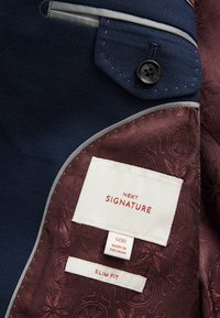 Granatowa marynarka z fakturowanej tkaniny z kontrastową bordową podszewką w wzory, zawiera metki "NEXT SIGNATURE", "40R" oraz "SLIM FIT."