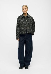Leopard print cropped jacket with button closure, gray and black tones. Paired with navy wide-leg denim pants and black slip-on shoes.