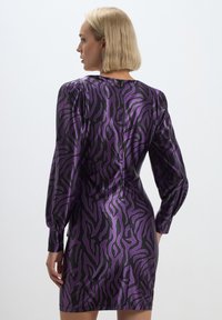 Abito a maniche lunghe viola e nero con motivo, caratterizzato da una texture setosa e una silhouette aderente, che mette in evidenza un design simile a quello di una zebra.