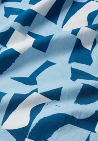 Cotton fabric featuring a blue and white abstract pattern with large, bold shapes and a smooth texture, creating a layered visual effect.
