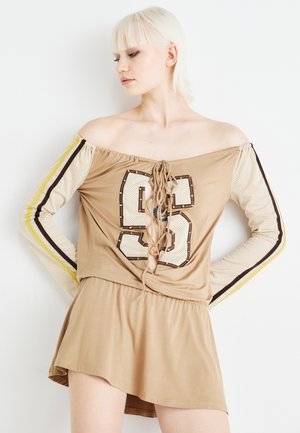 Beige off-shoulder kjole med snøre detaljer, mesh lange ærmer og et stort nummergrafik på forsiden. Inkluderer kontrasterende striber.