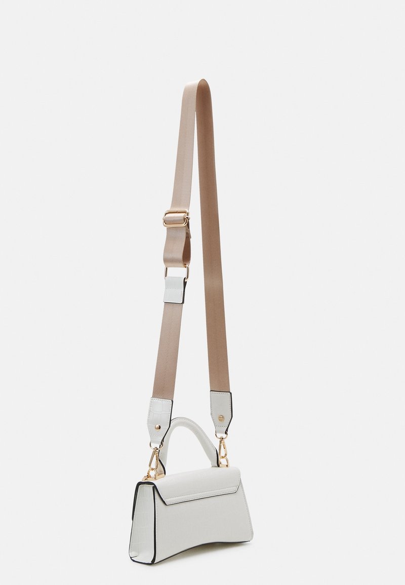 Sac à main structuré blanc avec bandoulière beige réglable et éléments métalliques dorés sur fond gris clair.