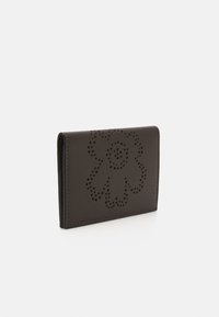 Mørkebrunt lær lommebok med blomstermotiv som har perforerte detaljer. Slank profil med rene kanter, minimalistisk stil.
