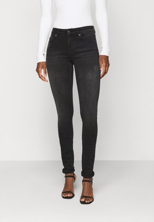 Jeans skinny pretos feitos de denim, com uma textura ligeiramente desbotada, design clássico de cinco bolsos e comprimento até ao tornozelo com punhos dobrados.