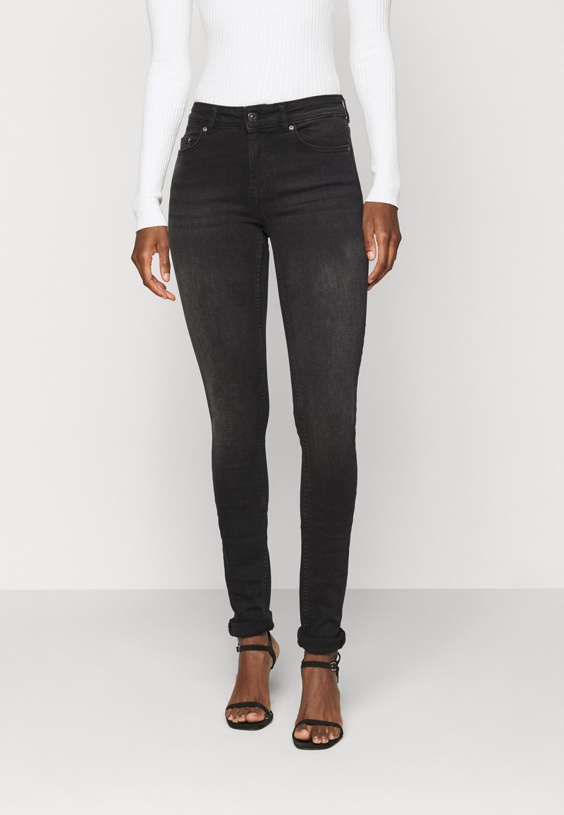 Jeans skinny pretos feitos de denim, com uma textura ligeiramente desbotada, design clássico de cinco bolsos e comprimento até ao tornozelo com punhos dobrados.