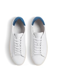 Vita lädersneakers med en blå hälflik, platta snörning och en strukturerad sula. Logotyp synlig på innersulan. Minimalistisk design.