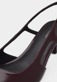 Γυναικείο ψηλοτάκουνο πέδιλο σε σκούρο μπορντό δερμάτινο βερνικωμένο, με μυτερή μύτη και μαύρη εσωτερική σόλα.