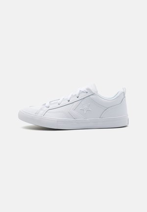 Sneaker bianca con una parte superiore in materiale sintetico liscio, punta texturizzata, lacci rotondi e un sottile logo a stella di lato. Suola in gomma con battistrada lavorato.