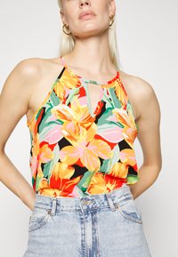 Top sem mangas com estampa floral e detalhe de abertura, apresentando cores vibrantes como amarelo, rosa e verde sobre um fundo preto; tecido leve.