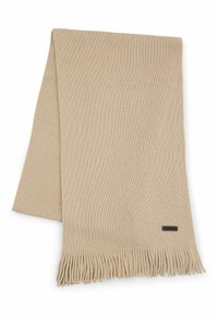 Beige villatakki, jossa on teksturoitu kuvio, frangeja reunoilla ja pieni musta etiketti toisessa päässä.