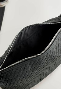 Schwarze geflochtene Lederhandtasche mit einem glatten Reißverschluss. Innen verfügt sie über ein schwarzes Stofffutter und eine kleine Reißverschlusstasche.