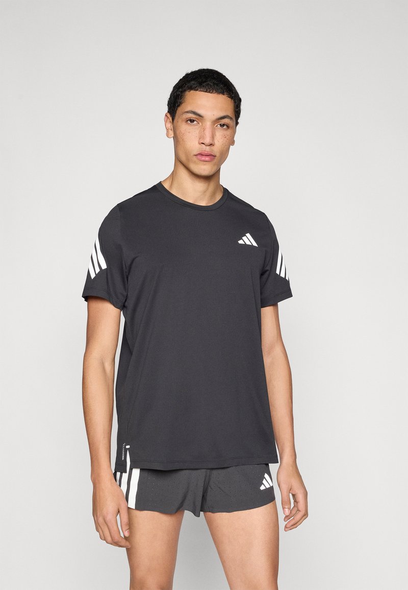 Must spordipluus lühikeste varrukatega, millel on valge Adidas logo ja kolm triipu õlgadel. Pehme, kerge kangas, ümara kaelusega.