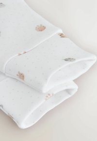 Witte stof met zachte, lichtgrijze stippen en kleine diermotieven in pasteltinten. De randen zijn netjes omgevouwen voor een strakke afwerking.