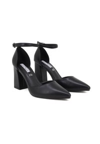 Scarpe con tacco alto in pelle nera, con punta affusolata, cinturino alla caviglia e tacco a blocco spesso. Texture liscia con un design minimalista e senza motivi.