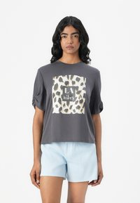 T-shirt gris à manches courtes avec un motif léopard arborant "LA vibes", associé à un short rayé bleu clair. Tissu doux, coupe décontractée.