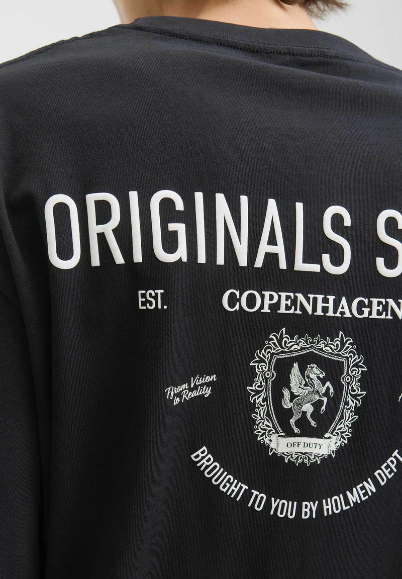 Zwarte katoenen t-shirt met witte tekst en een grafisch ontwerp met een wapenschild, inclusief een paard en decoratieve elementen.