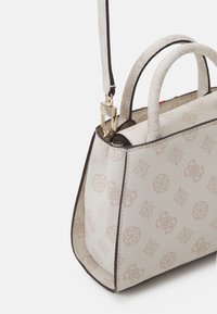 Sac à main en crème texturé avec une surface à motifs, des bordures foncées contrastantes, de courtes poignées et une bandoulière réglable avec un fermoir en or.