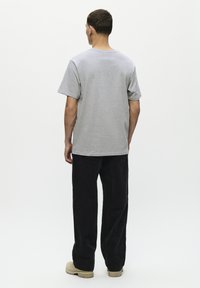 Grå bomulds T-shirt med afslappet pasform, korte ærmer og rund halsudskæring, parret med sorte kordfløjl bukser og beige fodtøj.