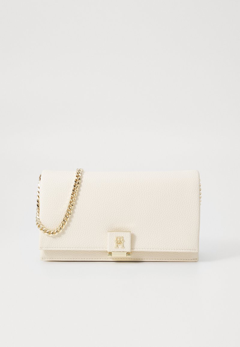 Cream-colored pebbled leather clutch with a gold chain strap and a rectangular clasp featuring a logo. Smooth texture; structured design.