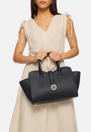 Black leather handbag with textured surface, structured shape, short handles, and a gold hardware accent on the front.