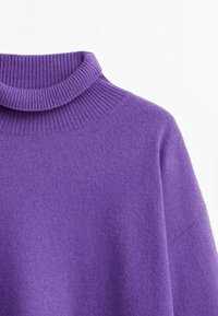 Purple sweater with a ribbed high neck. Soft, textured fabric and loose fit, featuring dropped shoulders and minimal seams.
