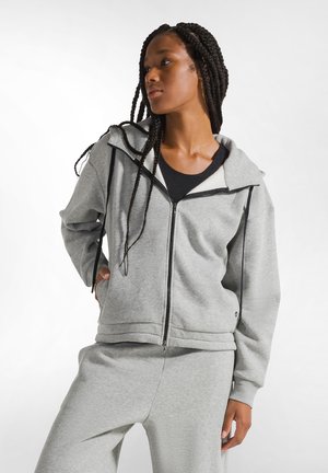 Gray zip-up hoodie with a hood, made of soft fabric, featuring contrasting black zippers and side pockets, paired with matching gray pants.