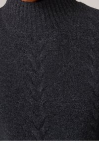 Gros plan d'un pull en maille torsadée gris foncé avec un col montant côtelé et une texture douce et duveteuse.