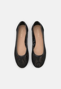Ballerine in pizzo nero con bordi neri lisci, soletta interna beige e un delicato motivo floreale visibile attraverso il pizzo.