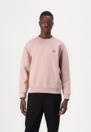Sweatshirt rose clair avec des poignets et un ourlet côtelés, arborant un petit logo de papillon jaune sur la poitrine gauche. Tissu doux et design décontracté.